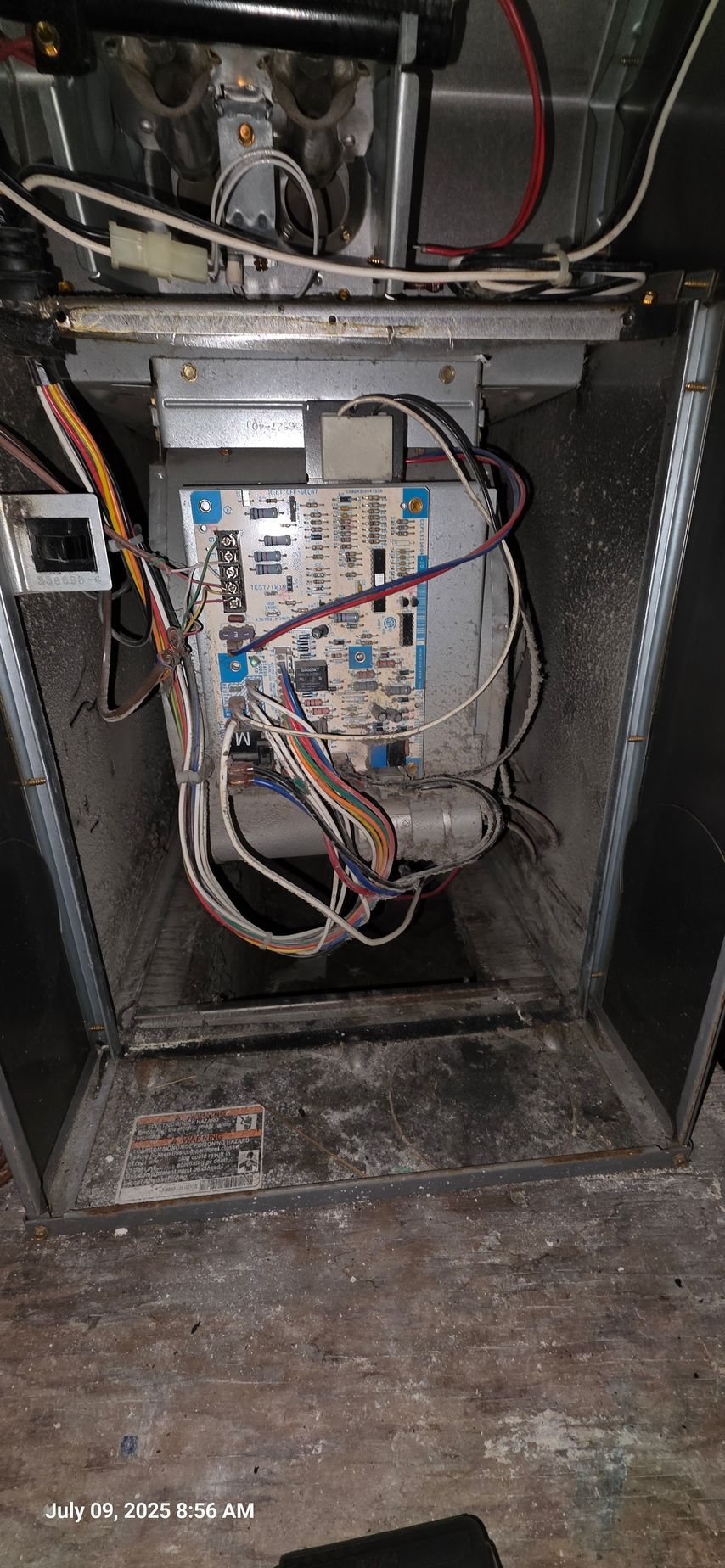 Furnace control board in a metal enclosure with wires and components visible.