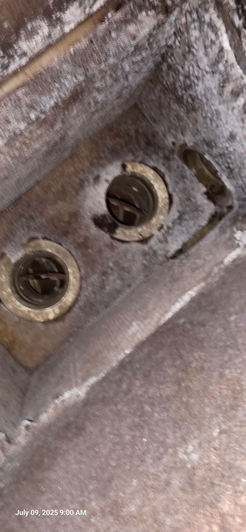 Close-up view of two screws inside a metal casing covered in white residue.