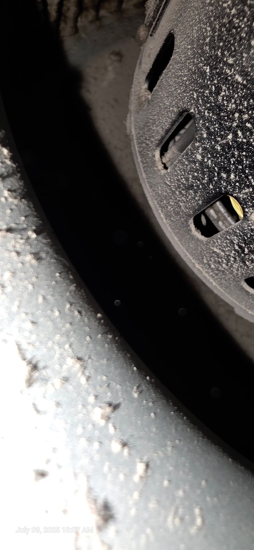 Close-up view of a dark space between a dirty tire and a black plastic wheel cover.