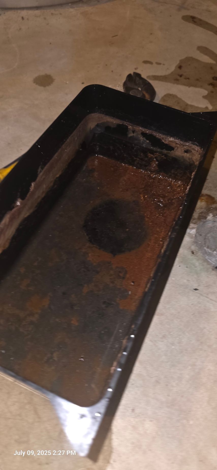 Rust-covered metal tray on a concrete floor.