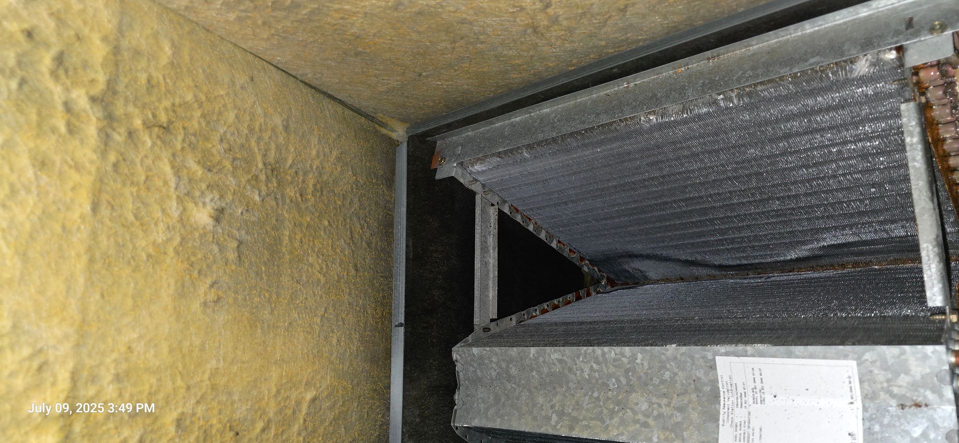 Interior view of an air conditioning unit; insulation on walls and ceiling; components covered with frost.