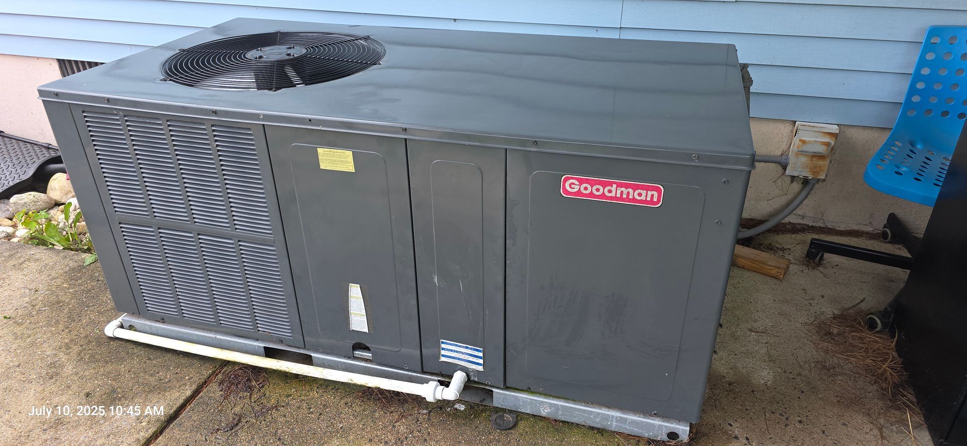 Goodman air conditioning unit outside a blue house.