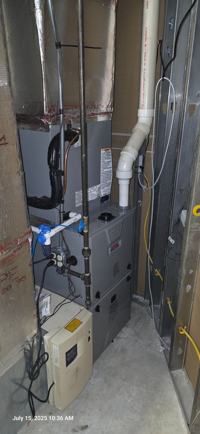 HVAC system with silver furnace, vent pipes, and a white control box in a tight space.