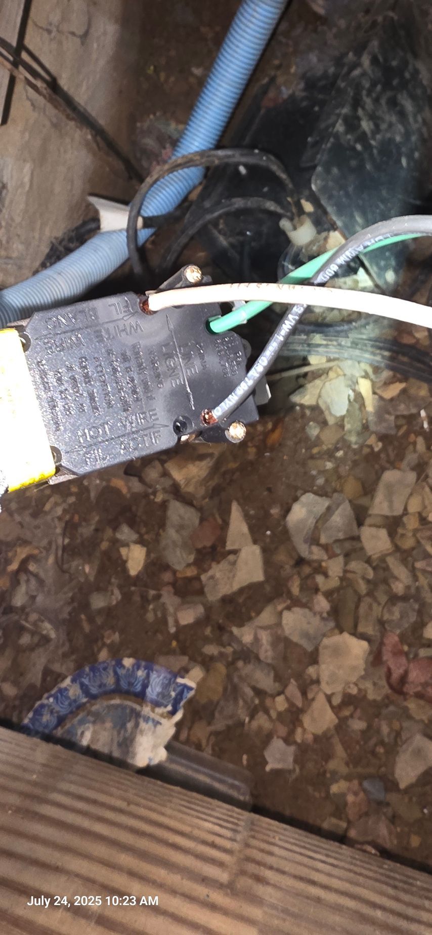 Electrical wiring and a black box in a gravelly environment. Blue and green wires are visible.