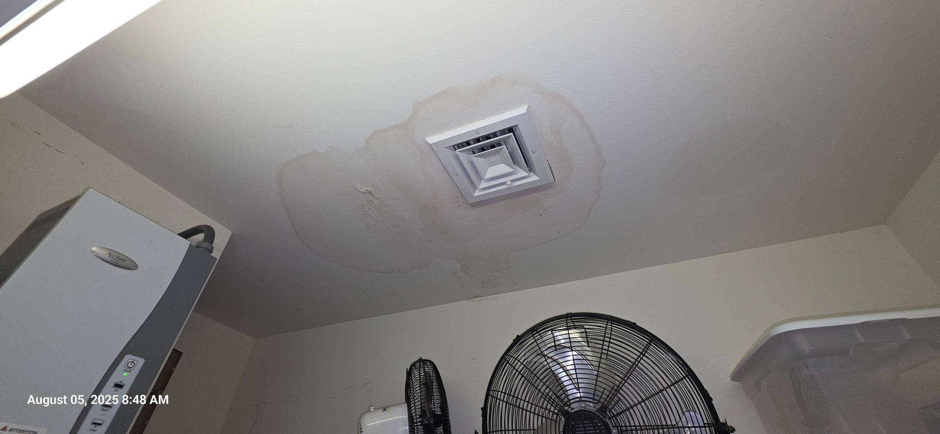 Water-stained ceiling around an air vent, in what appears to be a garage, with visible water damage.