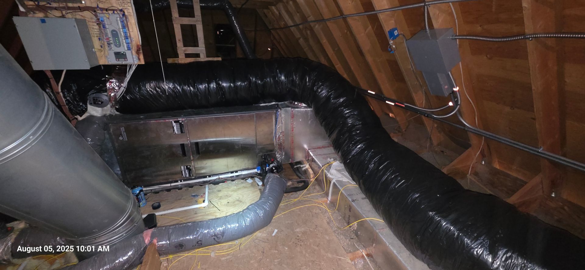 Attic with HVAC ductwork and other equipment installed. Wooden beams and insulation are visible.