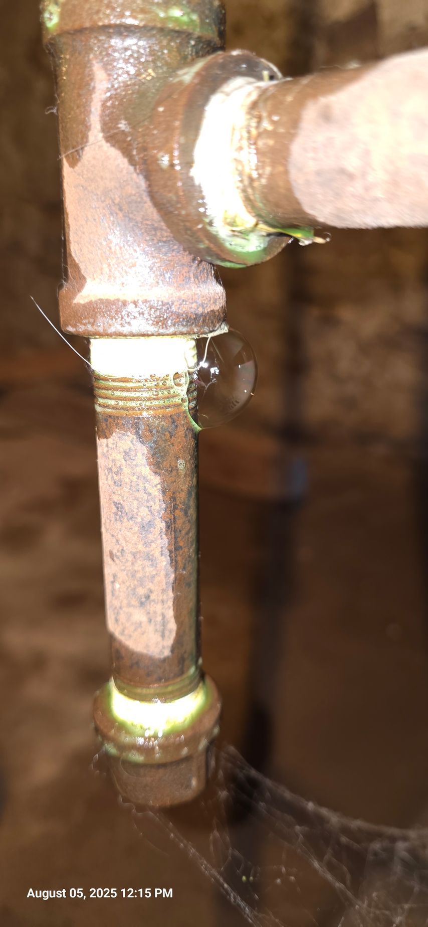 Leaking pipe joint, showing corrosion and liquid droplets on aged metal.