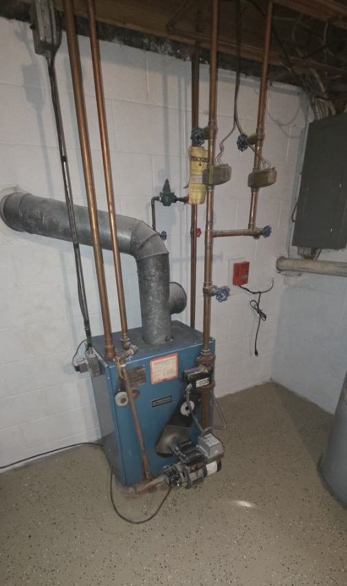 Blue boiler with copper pipes in a basement corner.