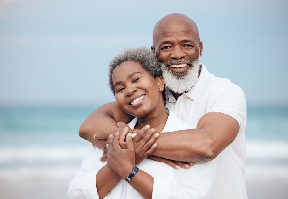 A man and a woman are hugging each other on the beach.