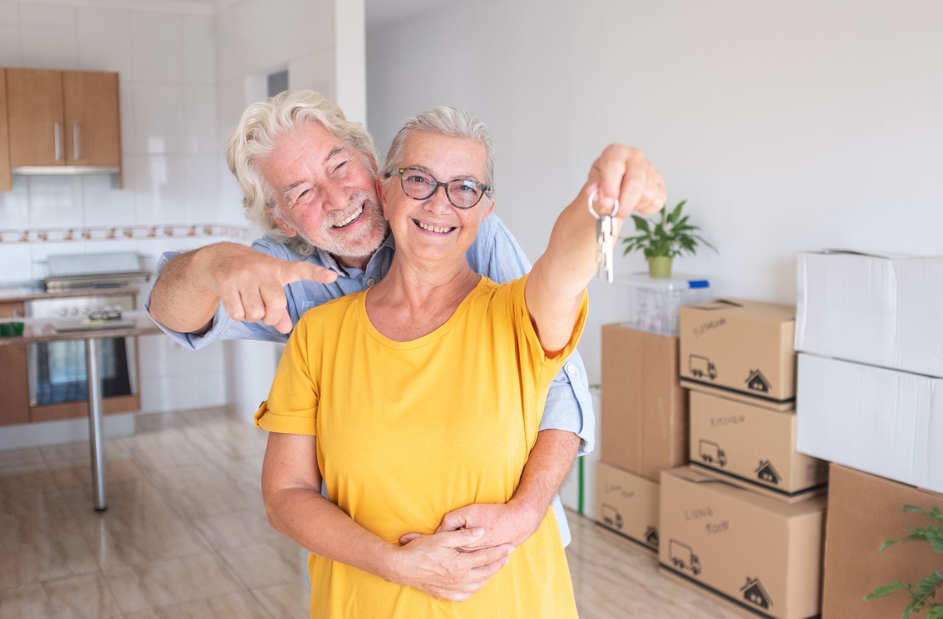 An elderly couple is holding the keys to their new home.