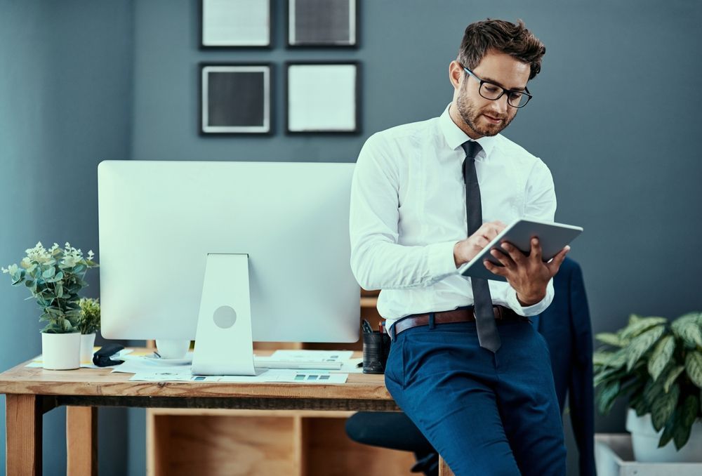 A man is sitting at a desk using a tablet computer.