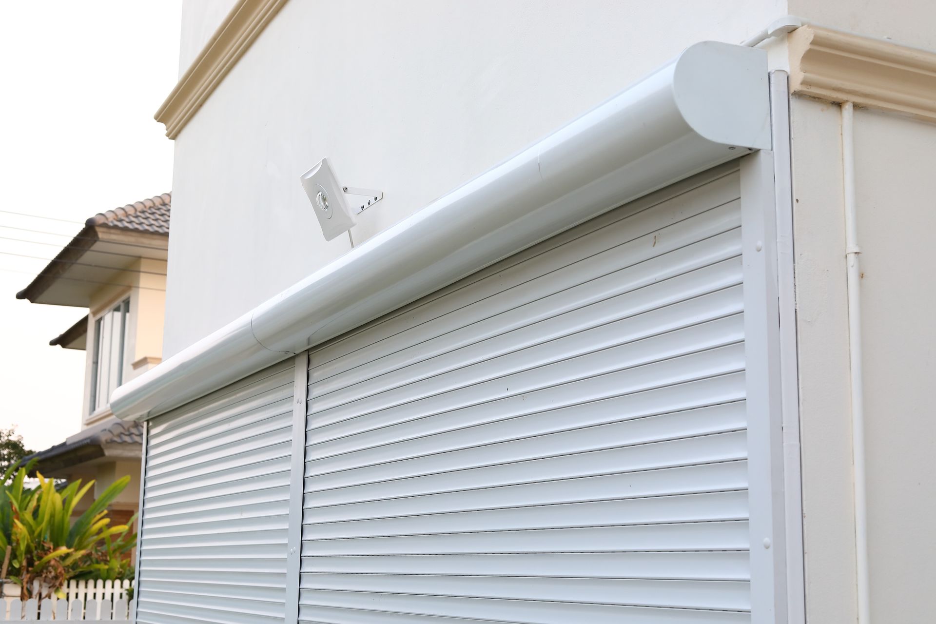 A white roller shutter door closed, providing security in a modern house.