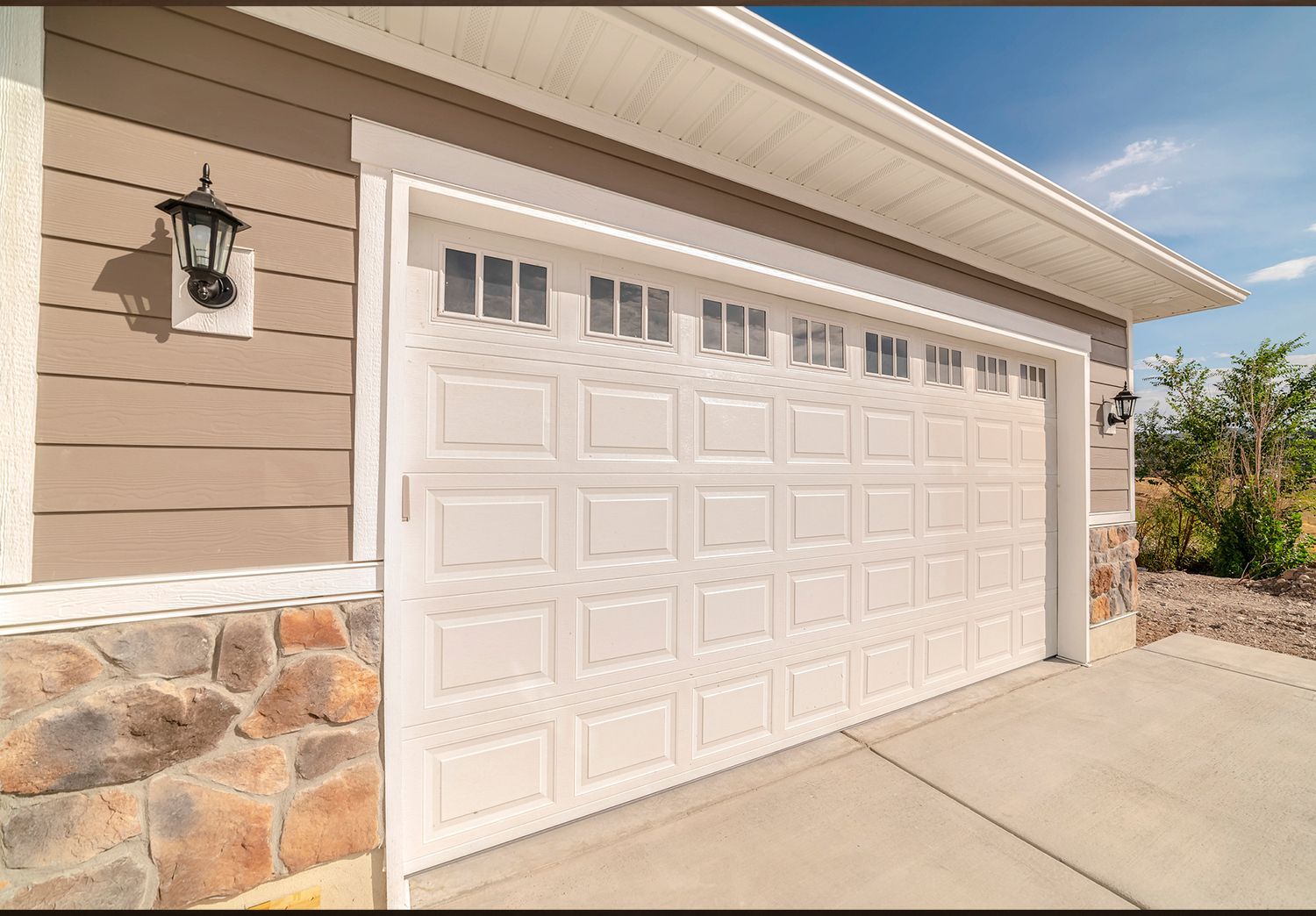 A white garage door of a modern home, showcasing garage door replacement services.