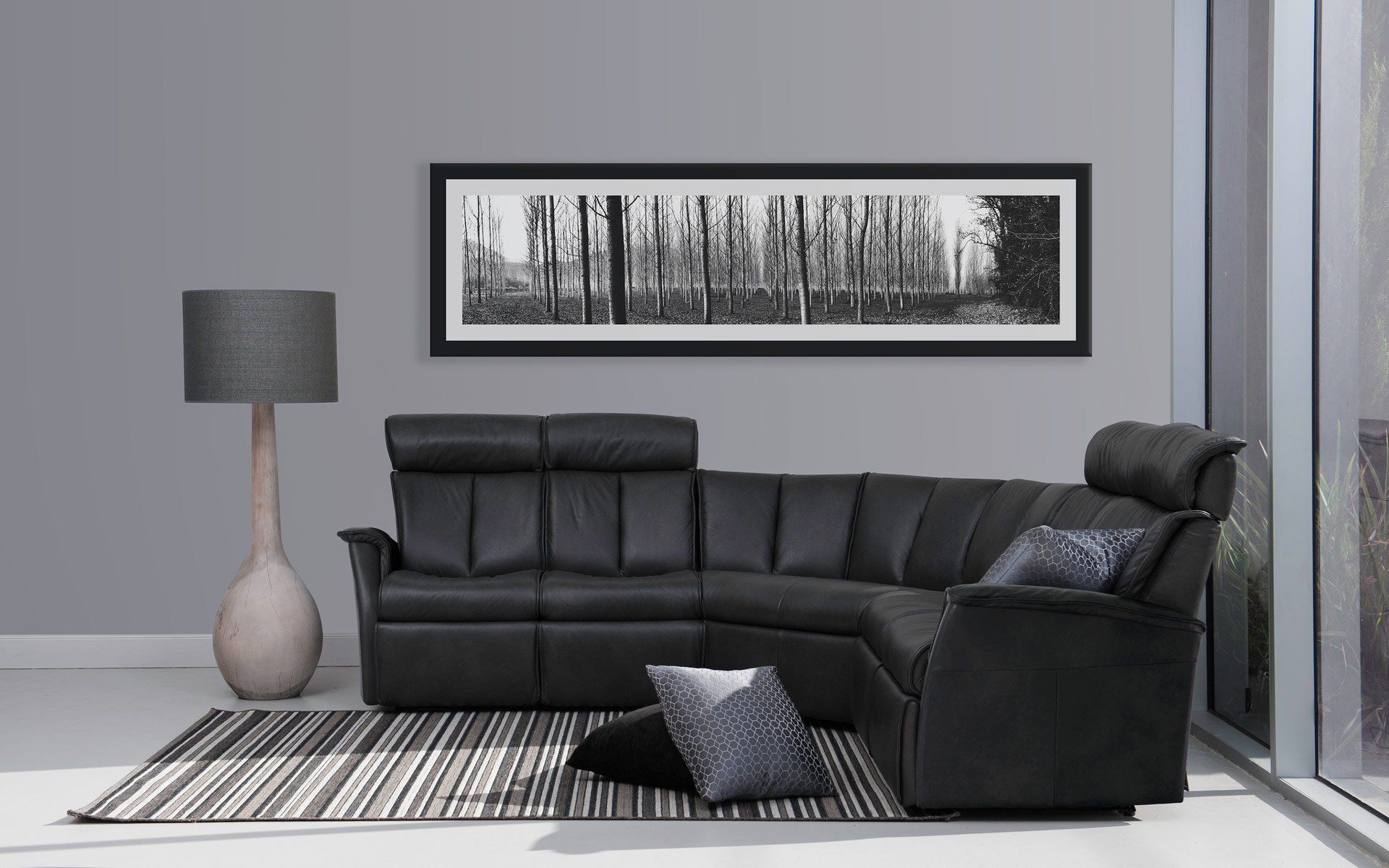 Black Leather Sectional Sofa in a Grey Room With a Floor Lamp — Hastings Specialty Furniture In Port Macquarie, NSW