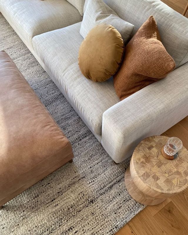 Beige Sofa With Pillows, a Rug, a Pouf, and a Wood Side Table — Hastings Specialty Furniture In Port Macquarie, NSW