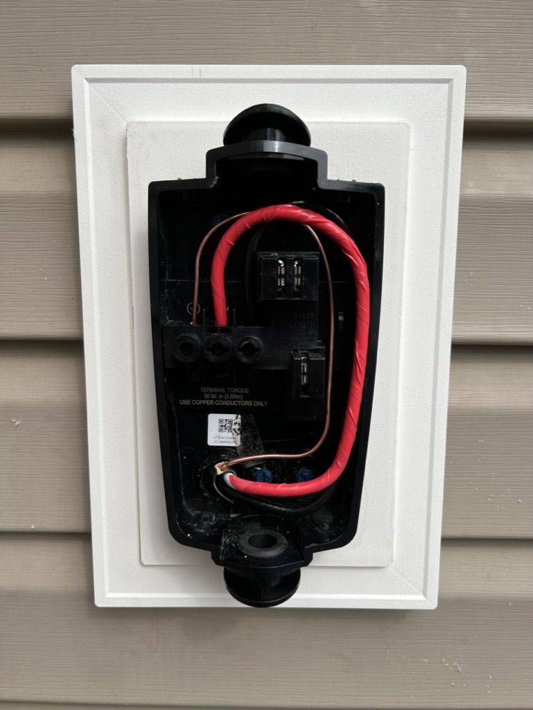 The inside of a doorbell with red wires coming out of it.