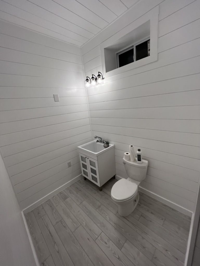 A bathroom with a toilet , sink , and window.