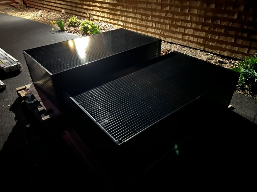 Two black boxes are sitting on the ground in front of a brick wall.