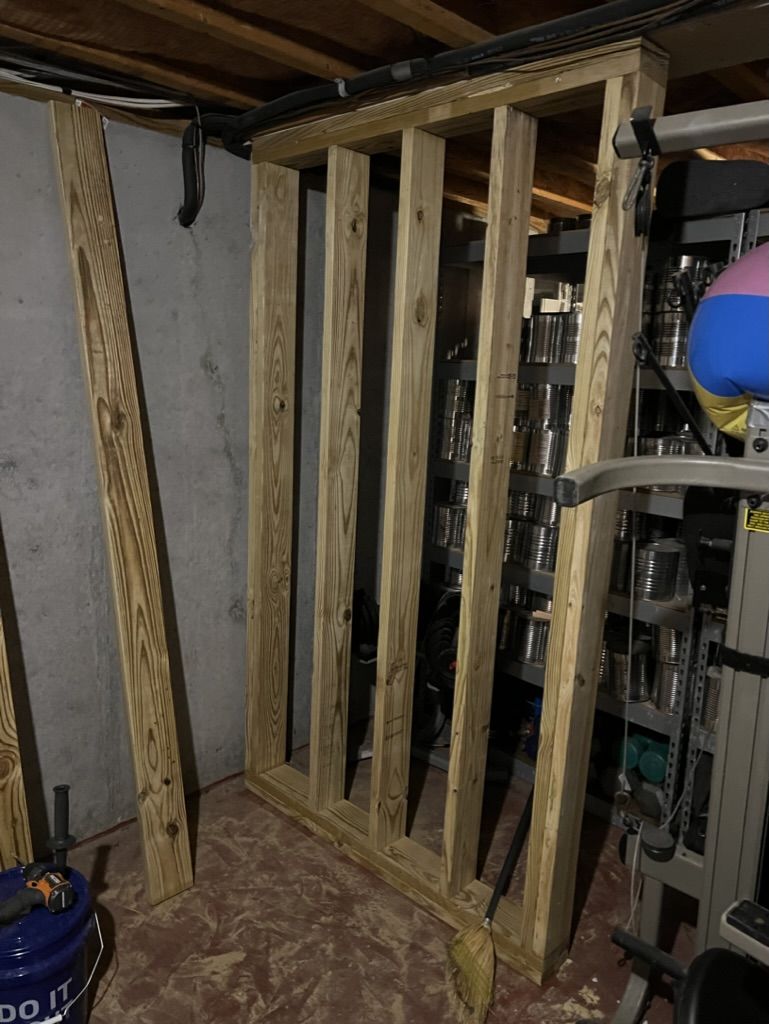 A wooden wall is being built in a basement.