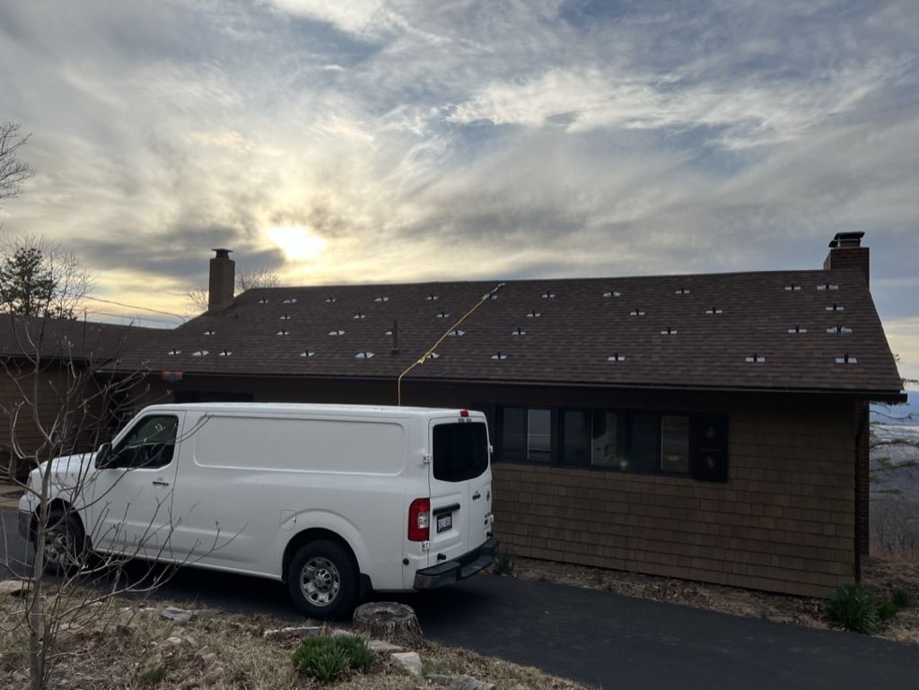 A white van is parked in front of a brick house.