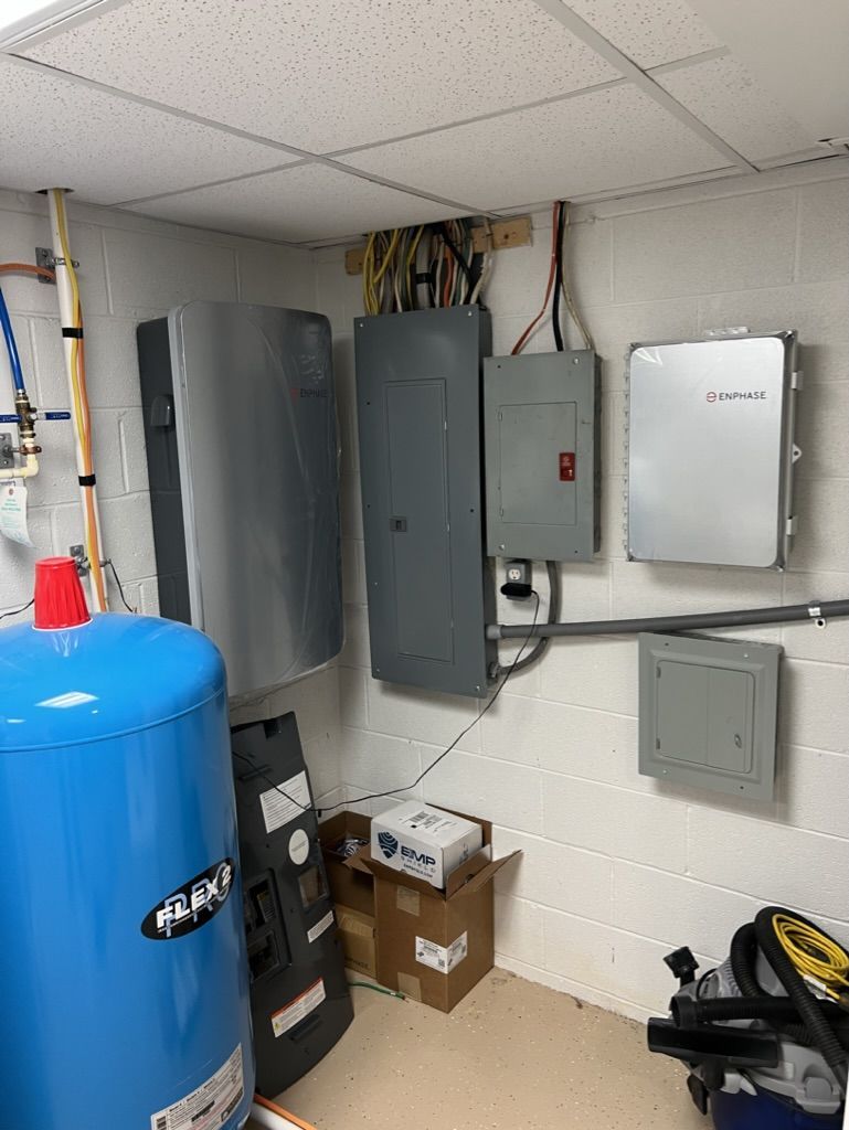 A room with a blue water heater , electrical panels , and a vacuum cleaner.