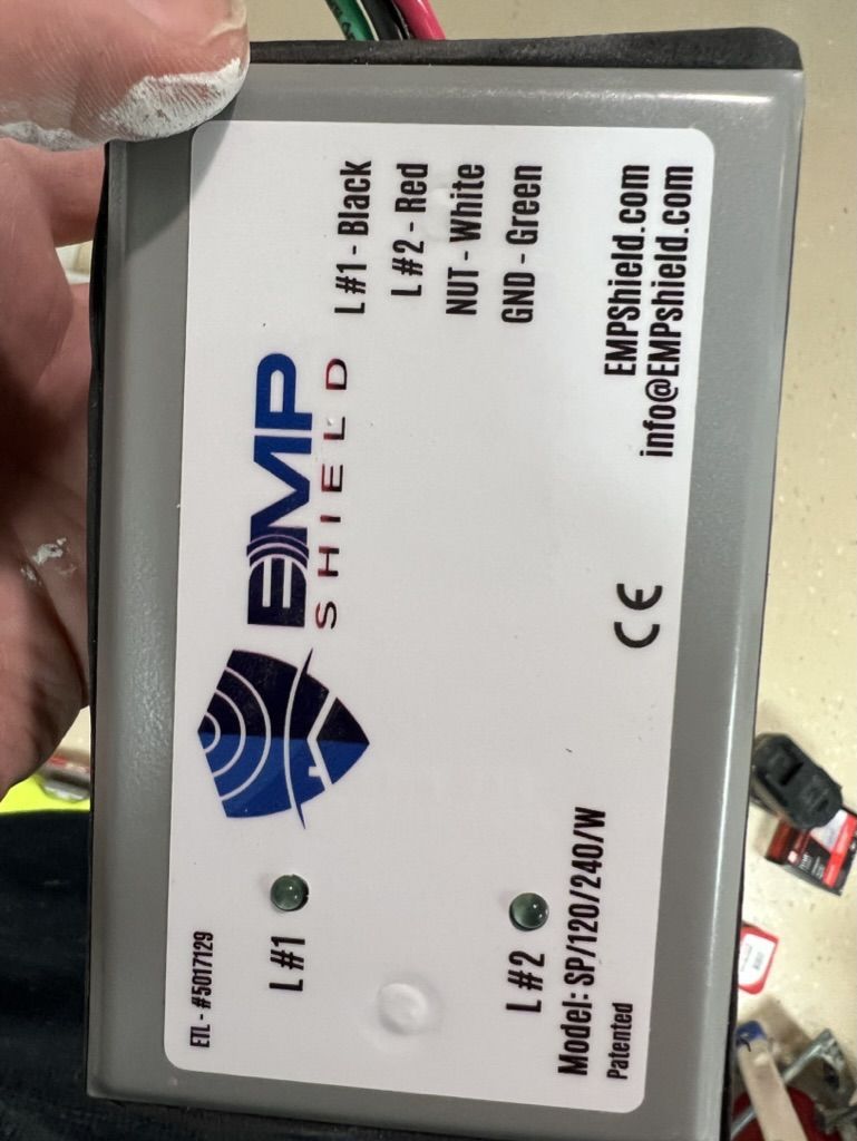 A person is holding a device that says emp shield on it