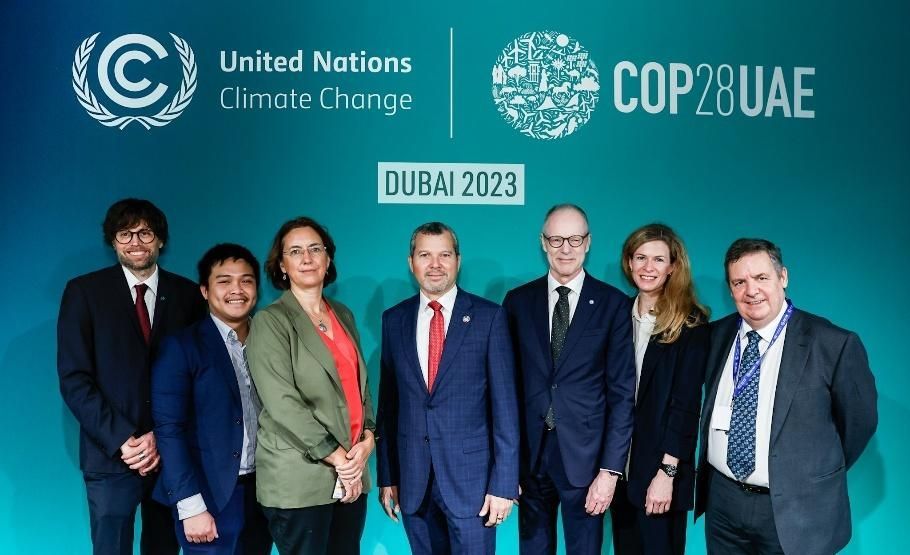 Group of people at COP28 in Dubai, 2023, in front of a branded backdrop.