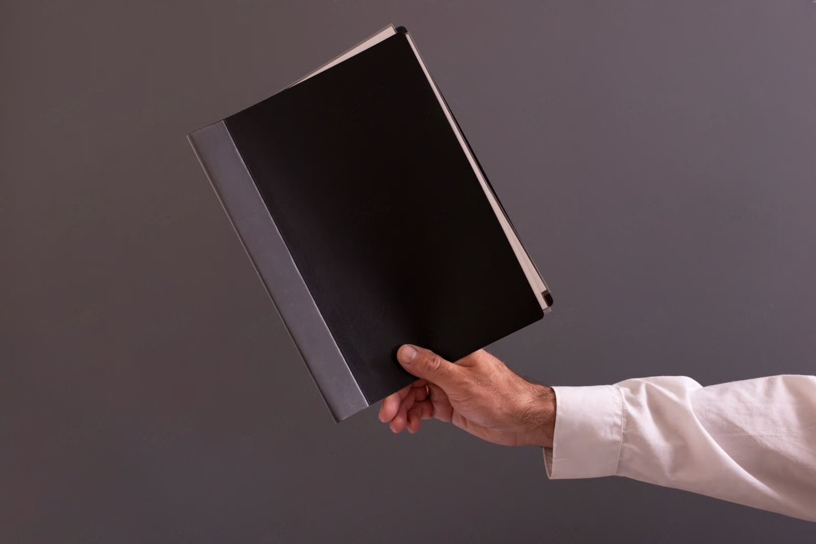 Mechanic in blue hat and jacket working on a truck tire, hood open, outdoors.