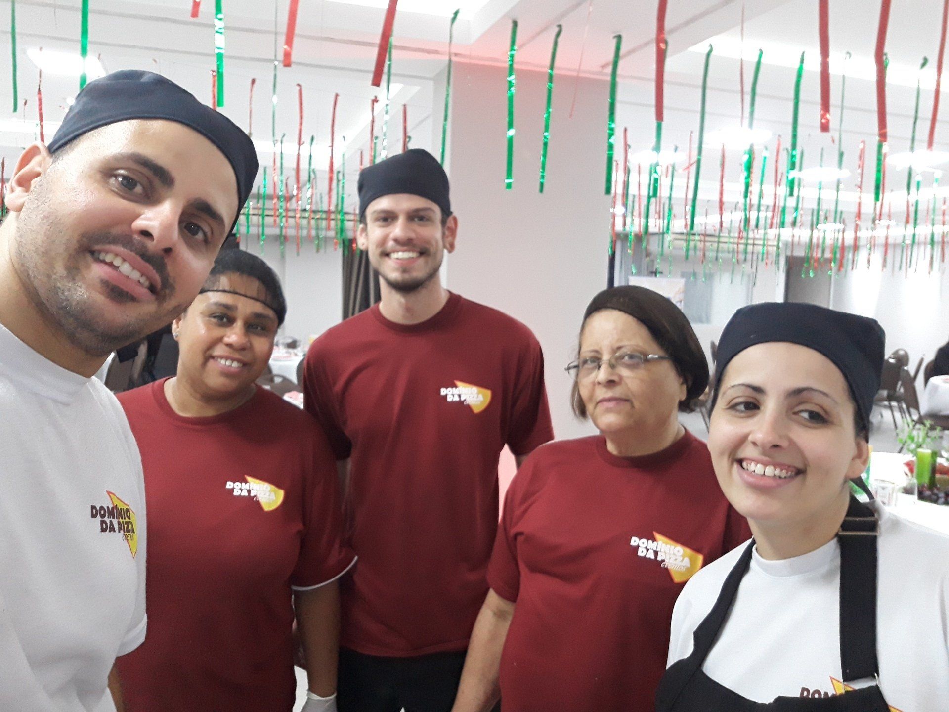 Um grupo de pessoas está posando para uma foto em uma cozinha.
