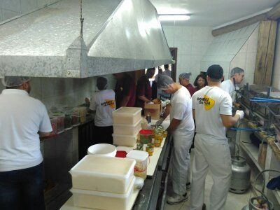 Um grupo de pessoas em uma cozinha com um homem vestindo uma camisa que diz 'a' nela