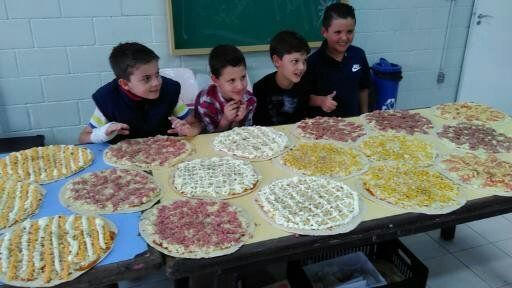 Um grupo de jovens rapazes está sentado em uma mesa com muitas pizzas.
