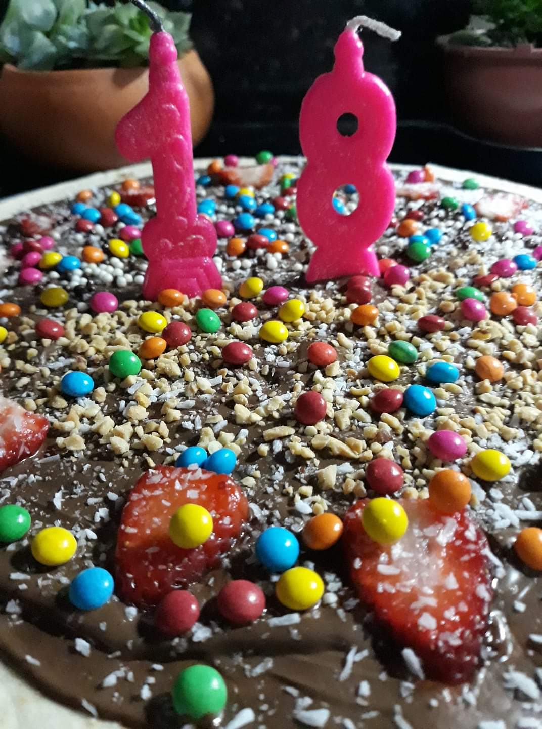 Um bolo de aniversário com uma vela rosa número 18 no topo