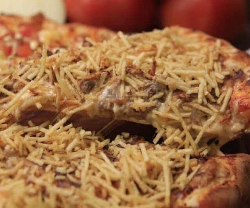 Um close de uma pizza com queijo e macarrão.