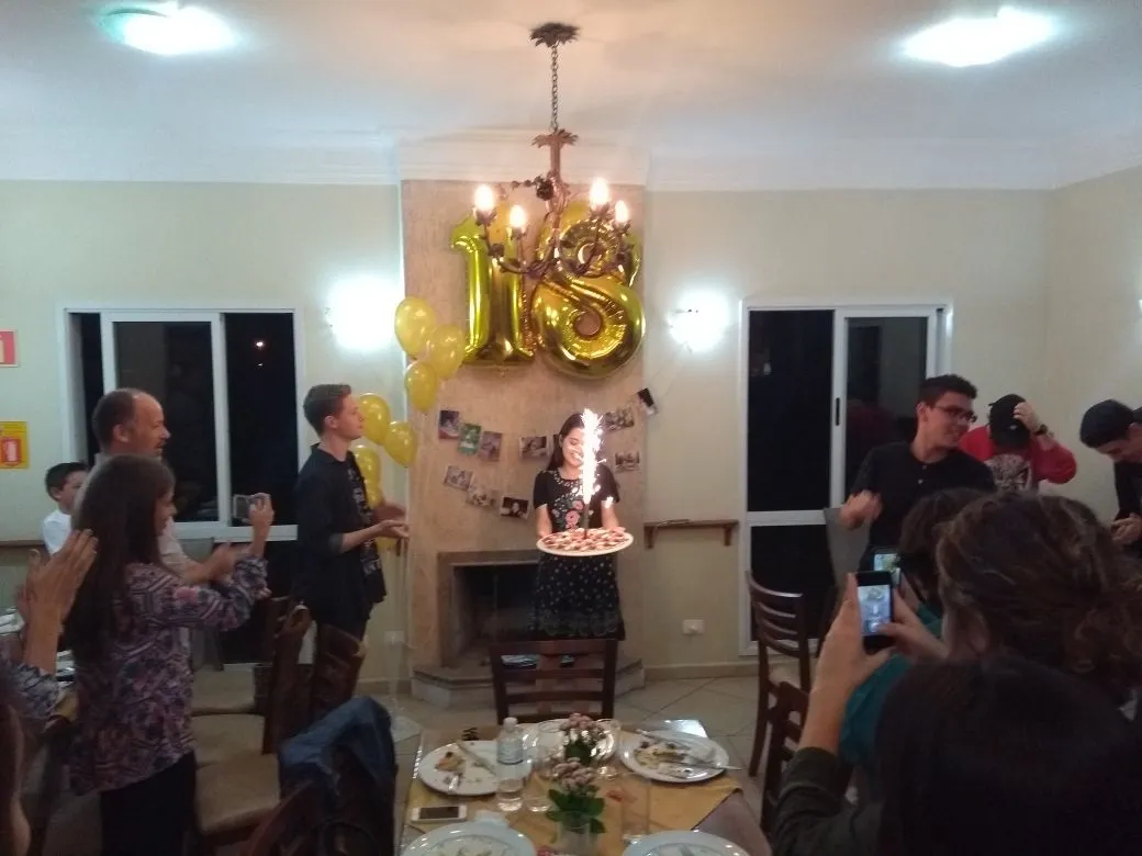 Uma mulher está comemorando seu aniversário de 18 anos com um bolo e balões