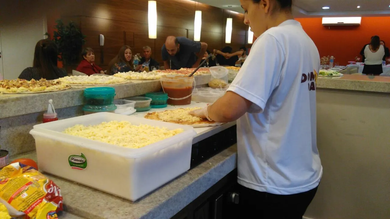 Uma mulher de camisa branca está fazendo uma pizza na cozinha.