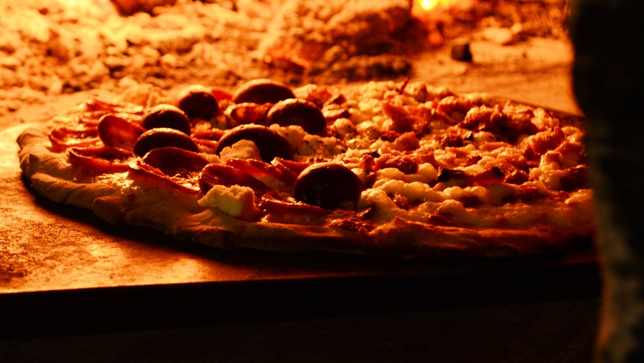 Uma pizza está sendo assada em um forno a lenha.