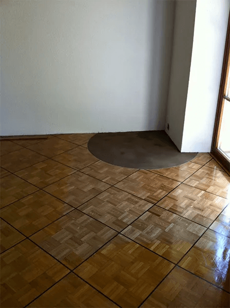 Une pièce vide avec un parquet et un mur blanc