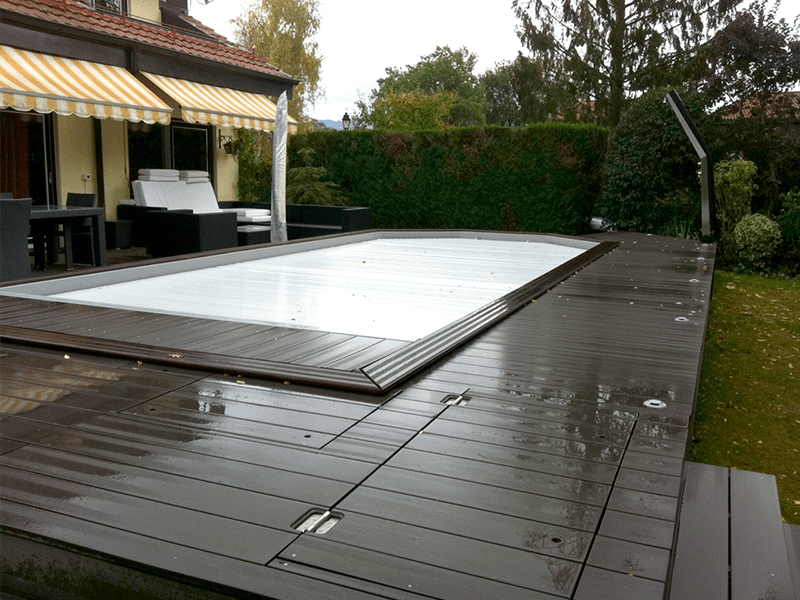 Une grande piscine est entourée d'une terrasse en bois.