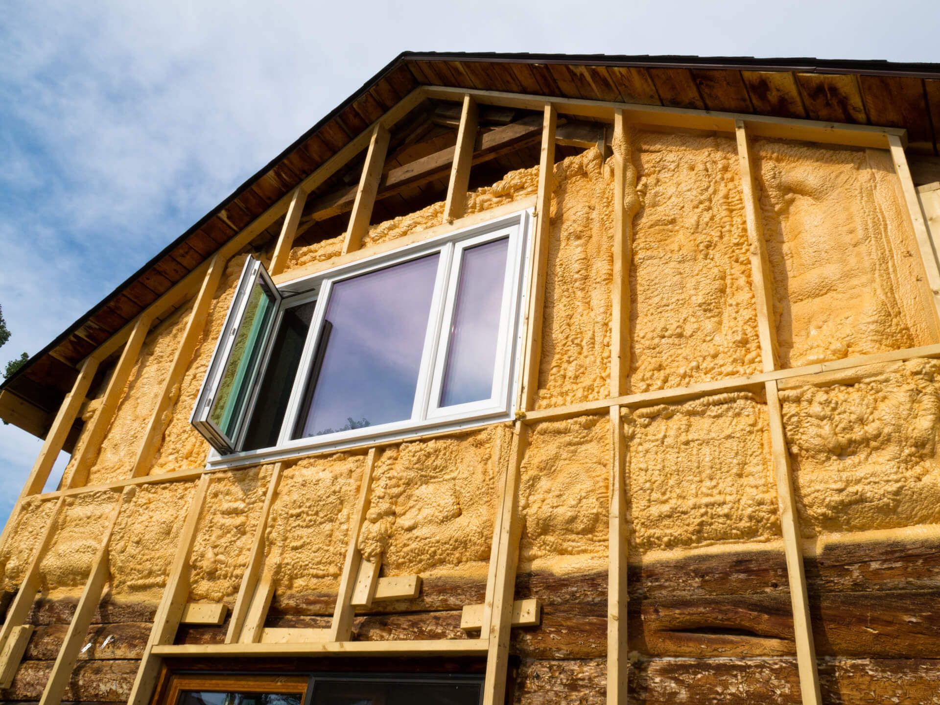 A house is being insulated with foam and has a window