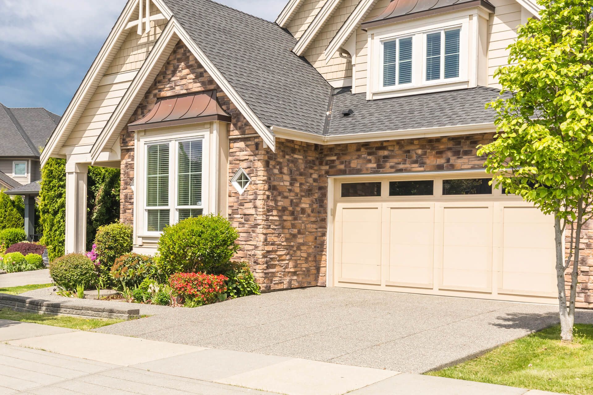 A large brick house with a large garage and a tree in front of it