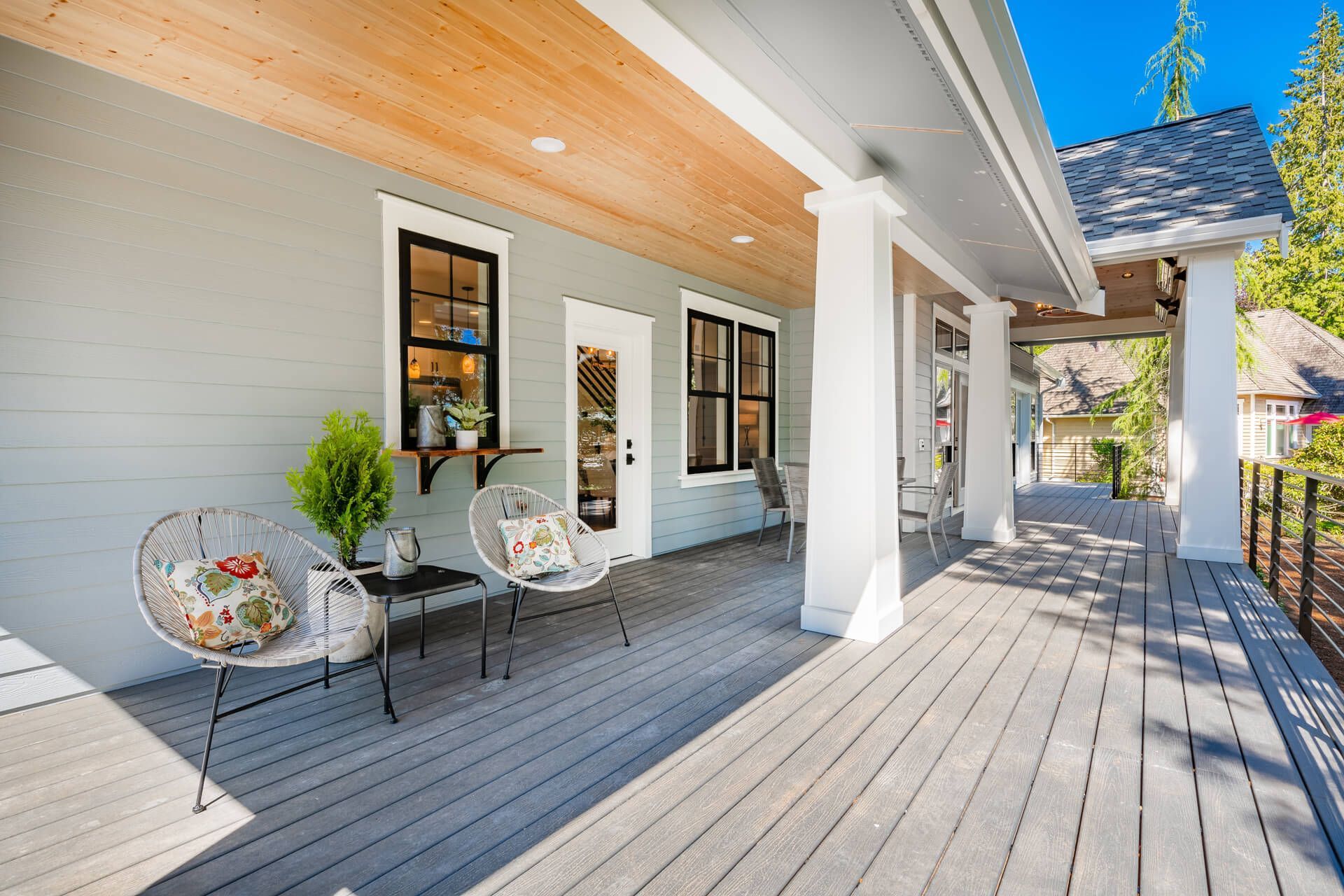 A large porch with chairs and a table in front of the house