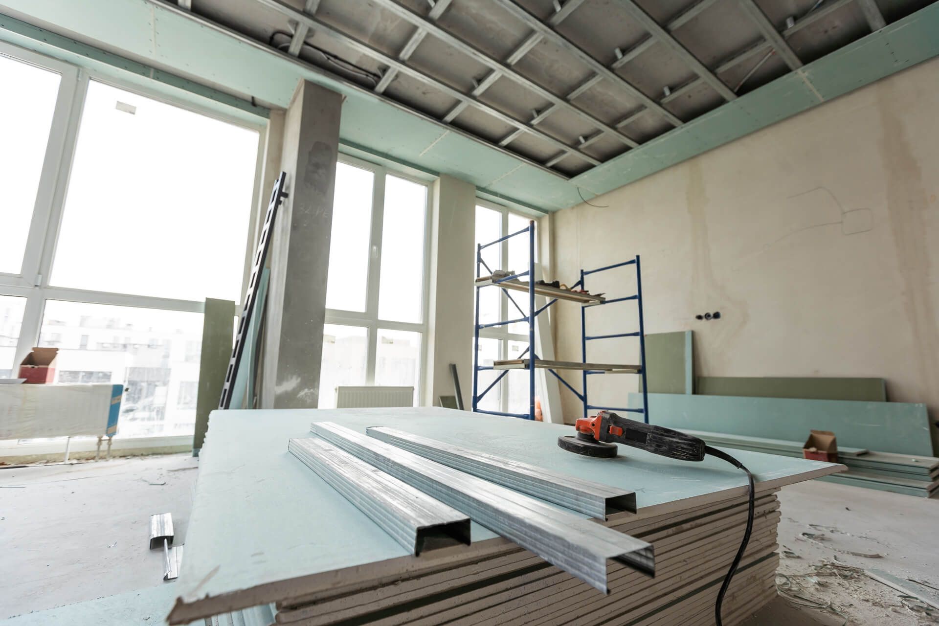 A room under construction with a lot of windows and a stack of drywall