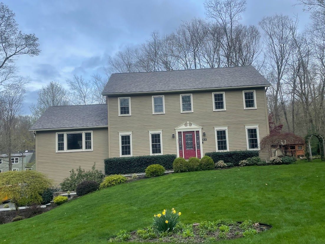 A large house with a red door is sitting on top of a lush green hill.