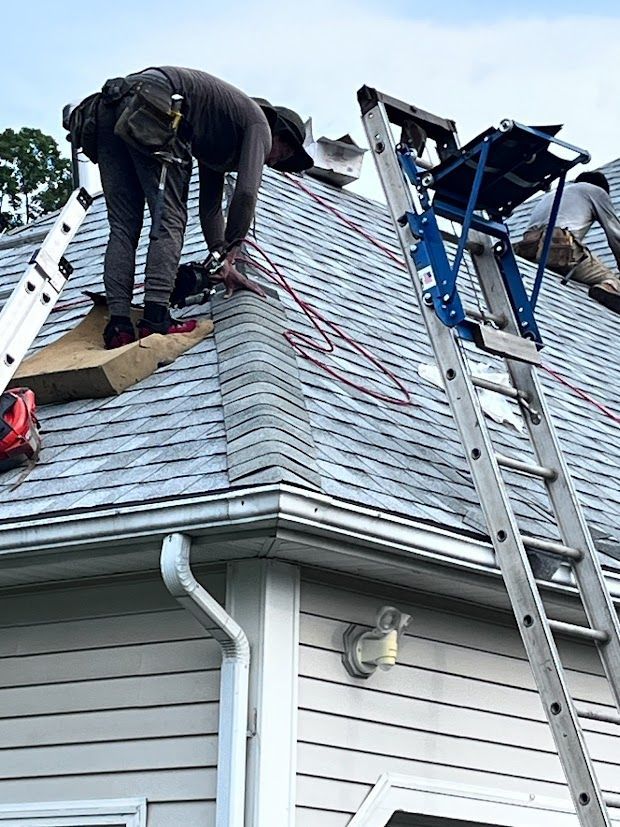 A man is working on the roof of a house with a ladder.