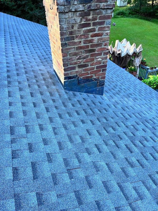 A blue roof with a brick chimney on top of it.