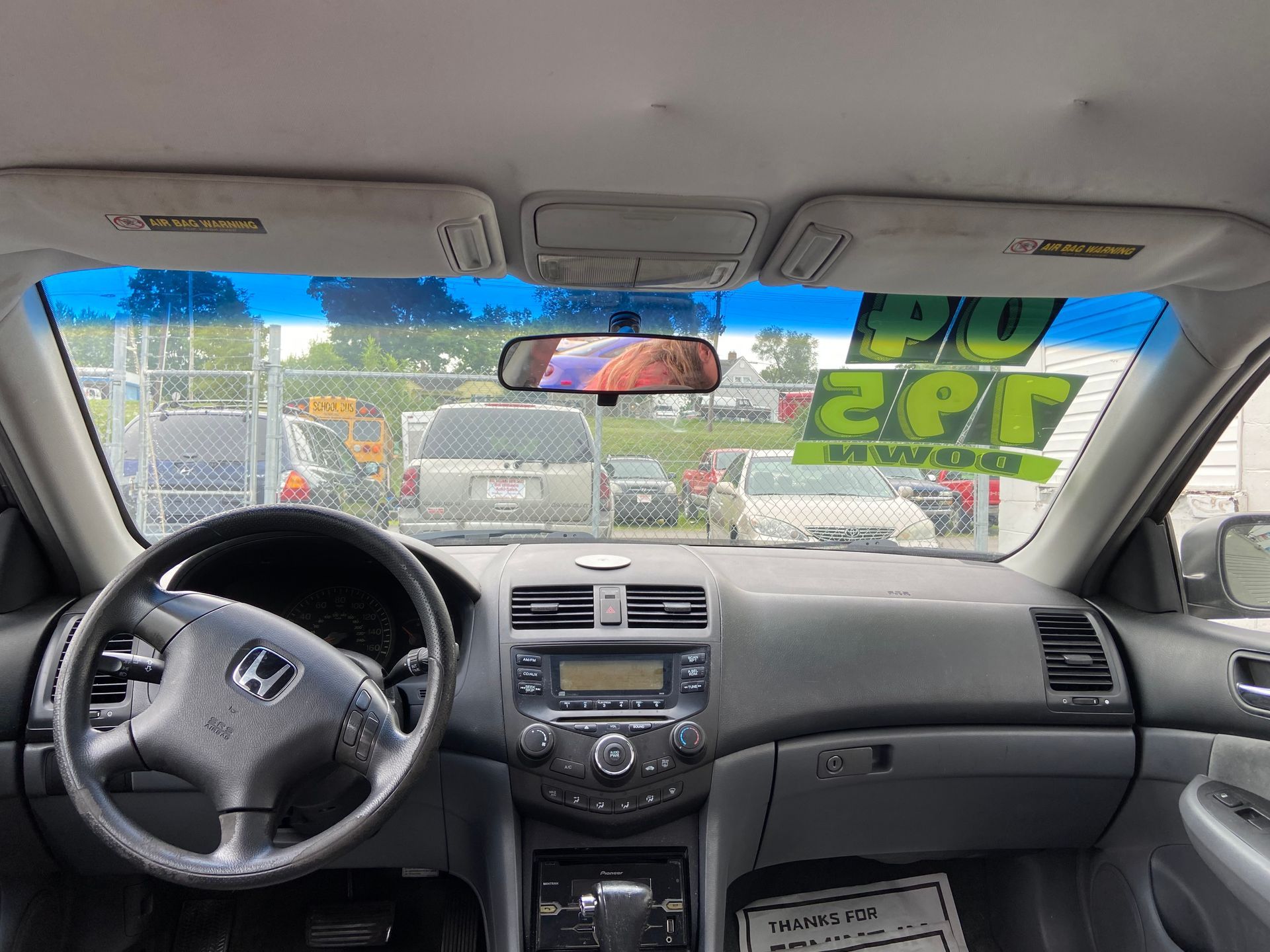 View from inside a Honda car at traffic, with dashboard, steering wheel, and cars ahead on a city street.
