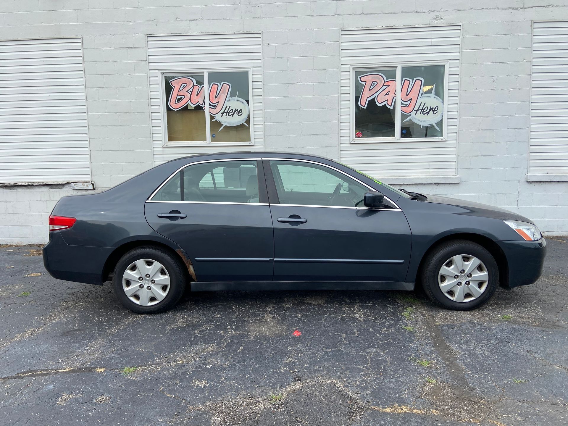 Dark blue sedan parked in front of a white building with storefront windows.