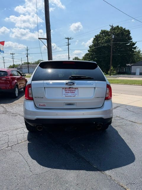 Rear view of a gray Toyota sedan parked on a roadside, with a cracked rear window and a dealer plate.