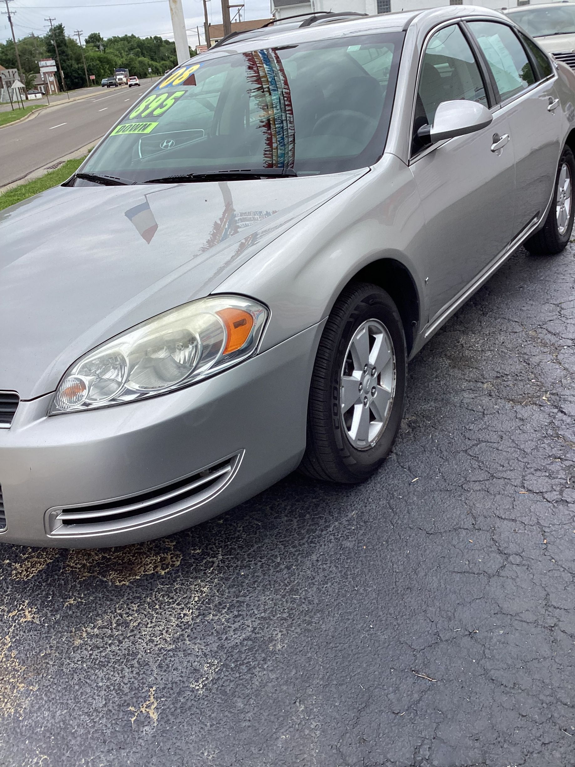 Silver sedan parked on a wet roadside under an overcast sky