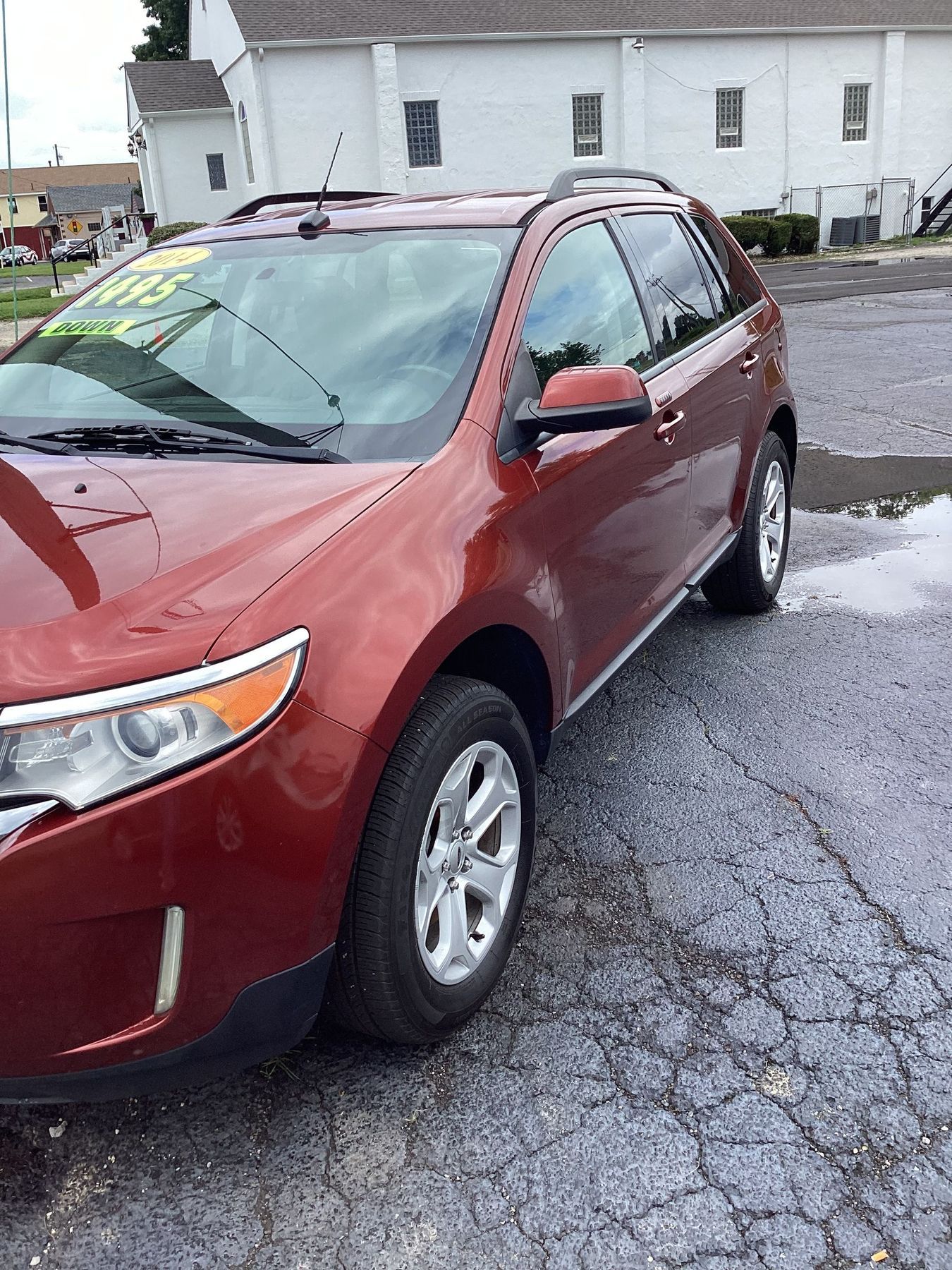 Red SUV parked on a wet lot in front of a white building.